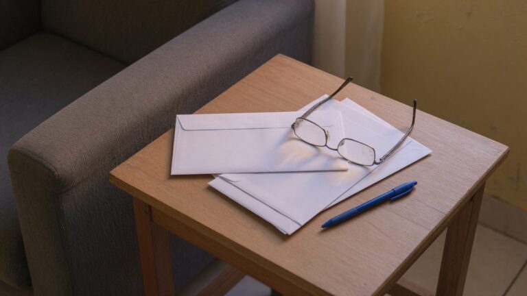 Mesinha de sala com correspondencia fechada e oculos de leitura